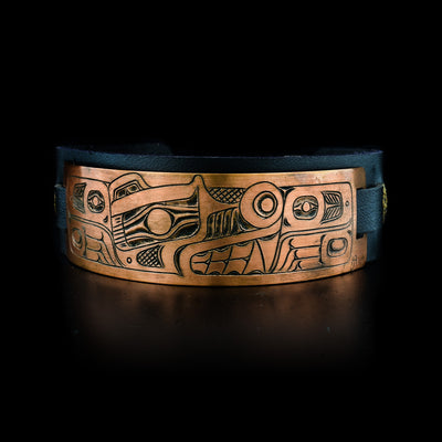 This leather cuff bracelet has a copper band attached at the top of the bracelet. The copper part of the bracelet has a depiction of the Bear carved into it.