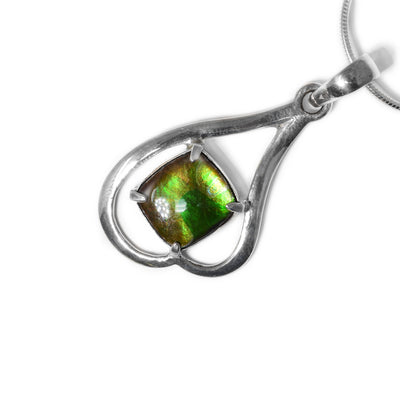 Square piece of ammolite set in pendant, shines different colours depending on how you look at it, predominantly green in colour. A sterling silver frame creates an uneven upside-down heart. Pendant is made of ammolite and sterling silver.