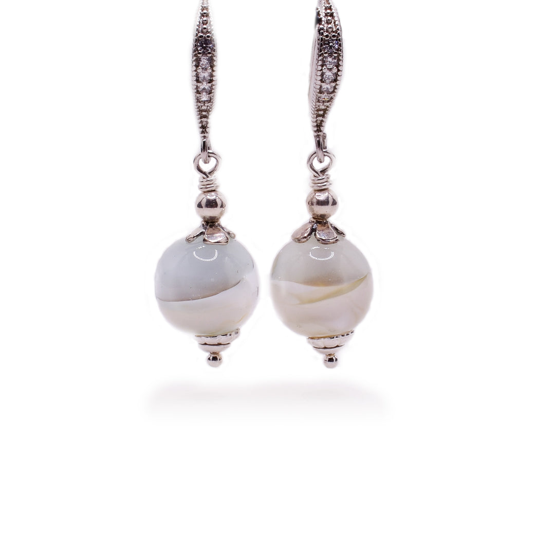 Each earring features a round white and light blue handmade lampworked glass bead on a sterling silver ear wire adorned with rhinestones. By Wendy Pierson.