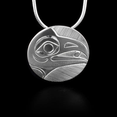 This sterling silver pendant is circle shaped and has a depiction of the Raven carved into it.