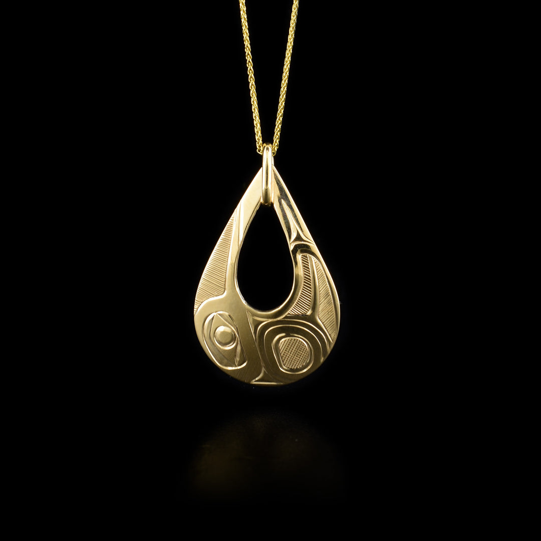 This 14K gold teardrop pendant has a cutout in the center and a depiction of the Thunderbird carved into the surface of the piece.