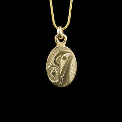 This Raven pendant is made from 14K gold and is small and oval shaped. There is a depiction of the Raven carved into the surface of the pendant and there is a thick jump ring for the piece.