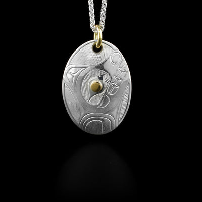 This sterling silver Bear pendant is oval shaped and has a depiction of the Bear carved into it. The eye of the Bear is a 14K gold stud and it has a gold jump ring. 