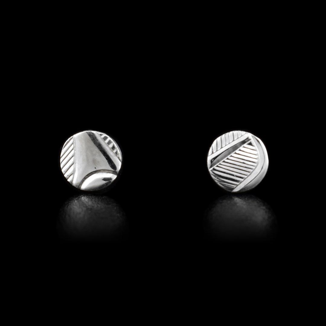 These small, circle stud earrings are made from sterling silver and have abstract carvings that depict the Raven on it.