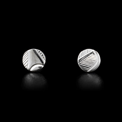 These small, circle stud earrings are made from sterling silver and have abstract carvings that depict the Raven on it.