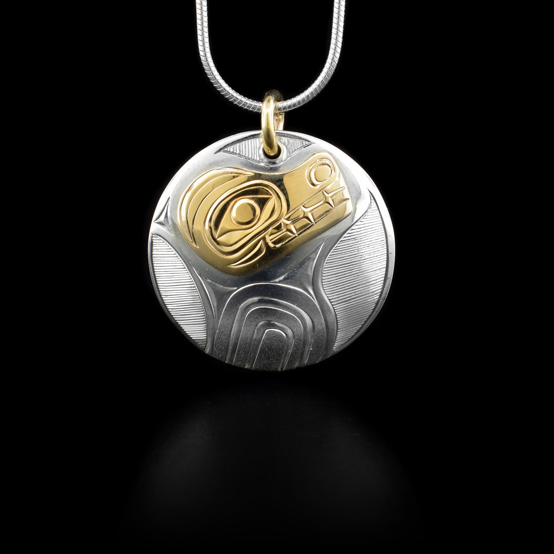 This sterling silver Bear pendant is circle shaped and has a depiction of the Bear carved into it. The face of the Bear is made from 14K gold.