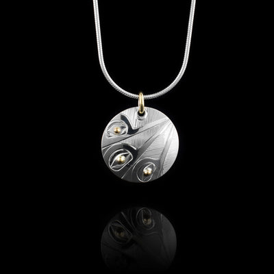 This sterling silver and 14K gold Hummingbird pendant is circle shaped and has three depictions of the Hummingbird carved into the piece. The legends have their beaks raised and they meet at the top of the pendant.