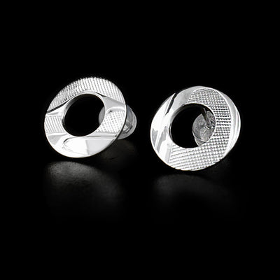 These sterling silver stud earrings are large circles with circle cutouts in the middle. There is an abstract depiction of the Raven carved into the earrings.