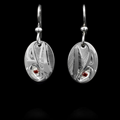 These oval, dangle earrings are made from sterling silver and has a depiction of the Raven carved into it. There are garnet gemstone embedded in the eyes of the Raven.