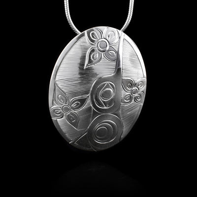 This sterling silver Hummingbird pendant is oval shaped and has a depiction of the Hummingbird and flowers carved into it.