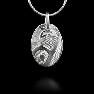 This small, oval Hummingbird pendant is made from sterling silver and has carvings that depict the Hummingbird.