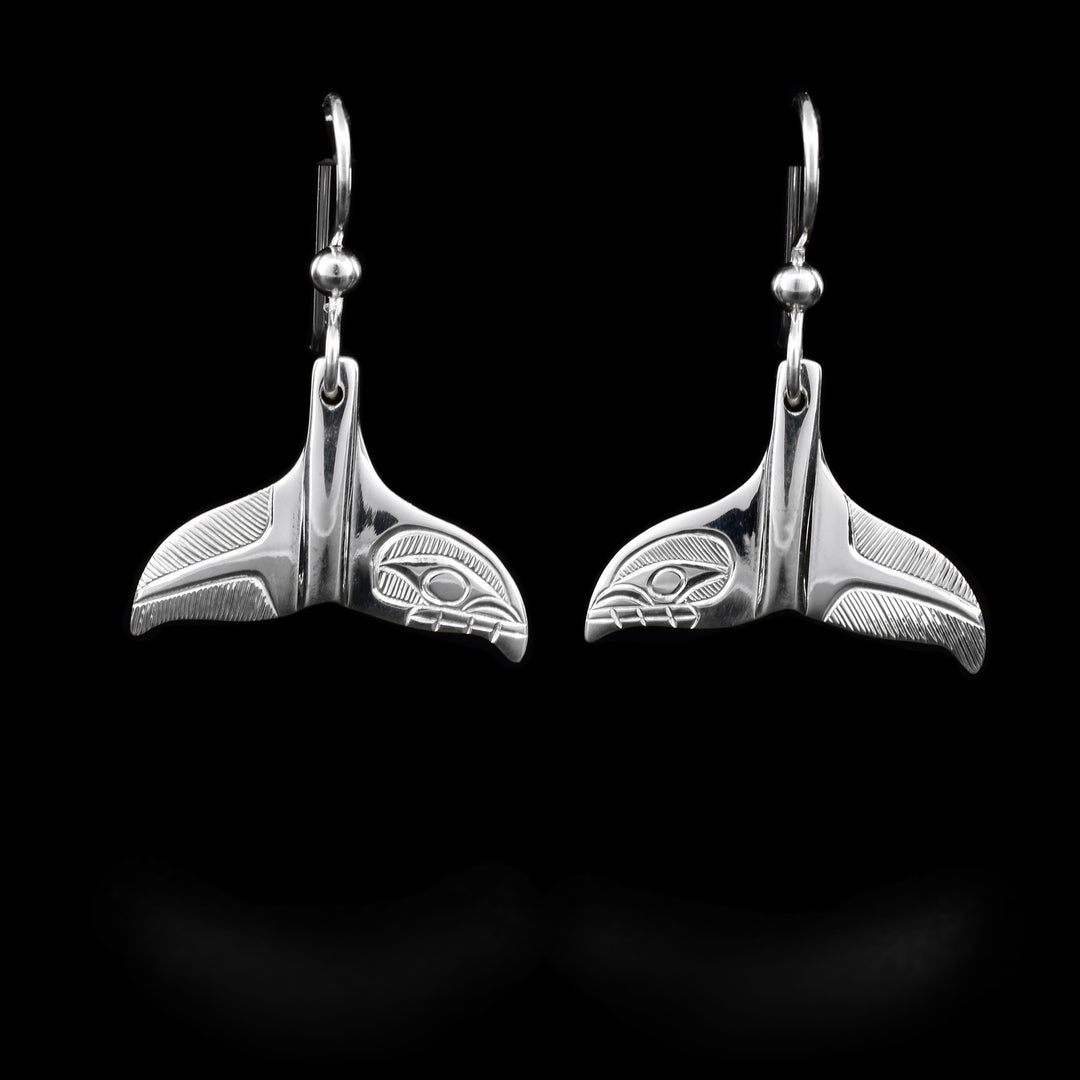 These sterling silver dangle earrings are shaped like a whales tail and have depictions of the Orca carved into them.