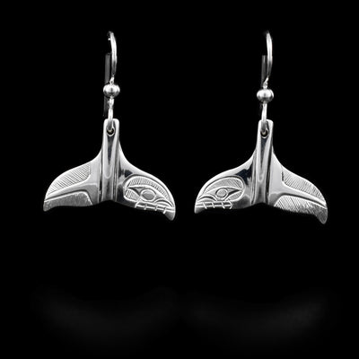 These sterling silver dangle earrings are shaped like a whales tail and have depictions of the Orca carved into them.