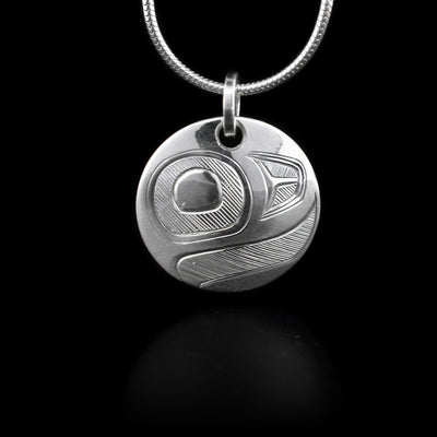 This sterling silver pendant is a small circle with carvings that depict an egg from the Salmon.