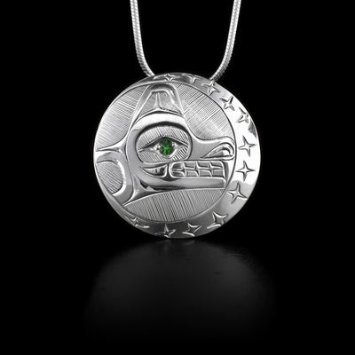 This sterling silver pendant is circular with carvings that depict the Wolf and the Moon. There is a tsavorite gem embedded into the eye of the wolf.
