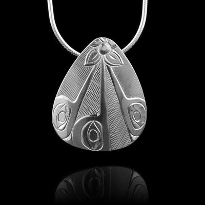 This oval pendant is made from sterling silver and has a wide. teardrop shape. There are carvings on the surface of the piece depicting three, Hummingbird legends looking upwards and their beaks meet at the top of the pendant. Where their beaks meet, there is a flower. In the space behind the legends there are hatching lines.