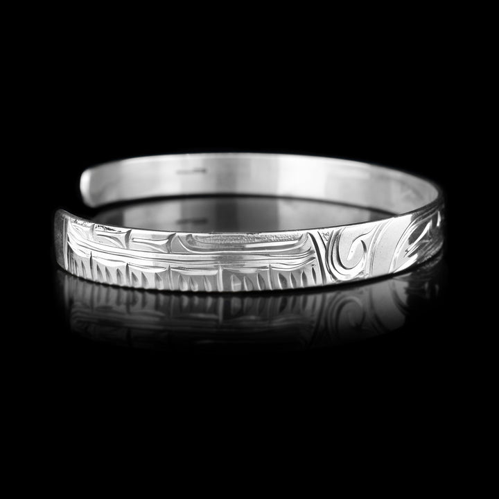 Left angle photo of the cuff bracelet shows carvings representing the wing and feathers of the hummingbird.