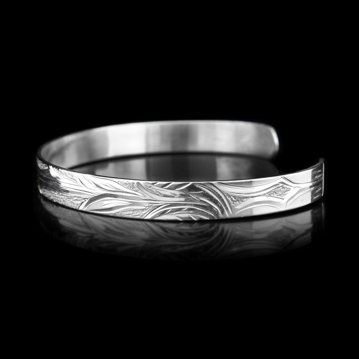 Right angle photo of the cuff bracelet shows carvings representing the flower the hummingbird is drinking from and its long stem.