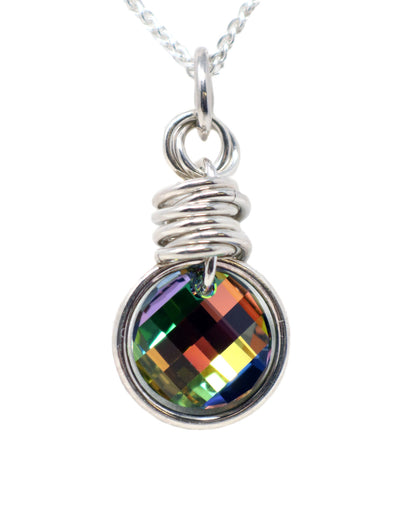 This Swarovksi crystal pendant features a iridescent and colorful Swarovski crystal that reflects colors including red, yellow, purple, and green. The crystal is large, round and is framed by a larger, sterling silver hoop. The crystal is always hanging form a silver chain link that has several other chain links stacked vertically on it.