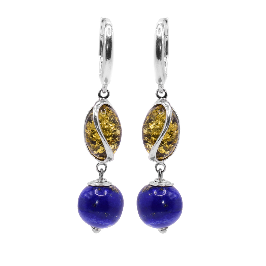 These amber dangle earrings have oval shaped amber beads with a curvy sterling silver designs encasing it. below them, there are sphere shaped lapis lazuli beads that are dangling.