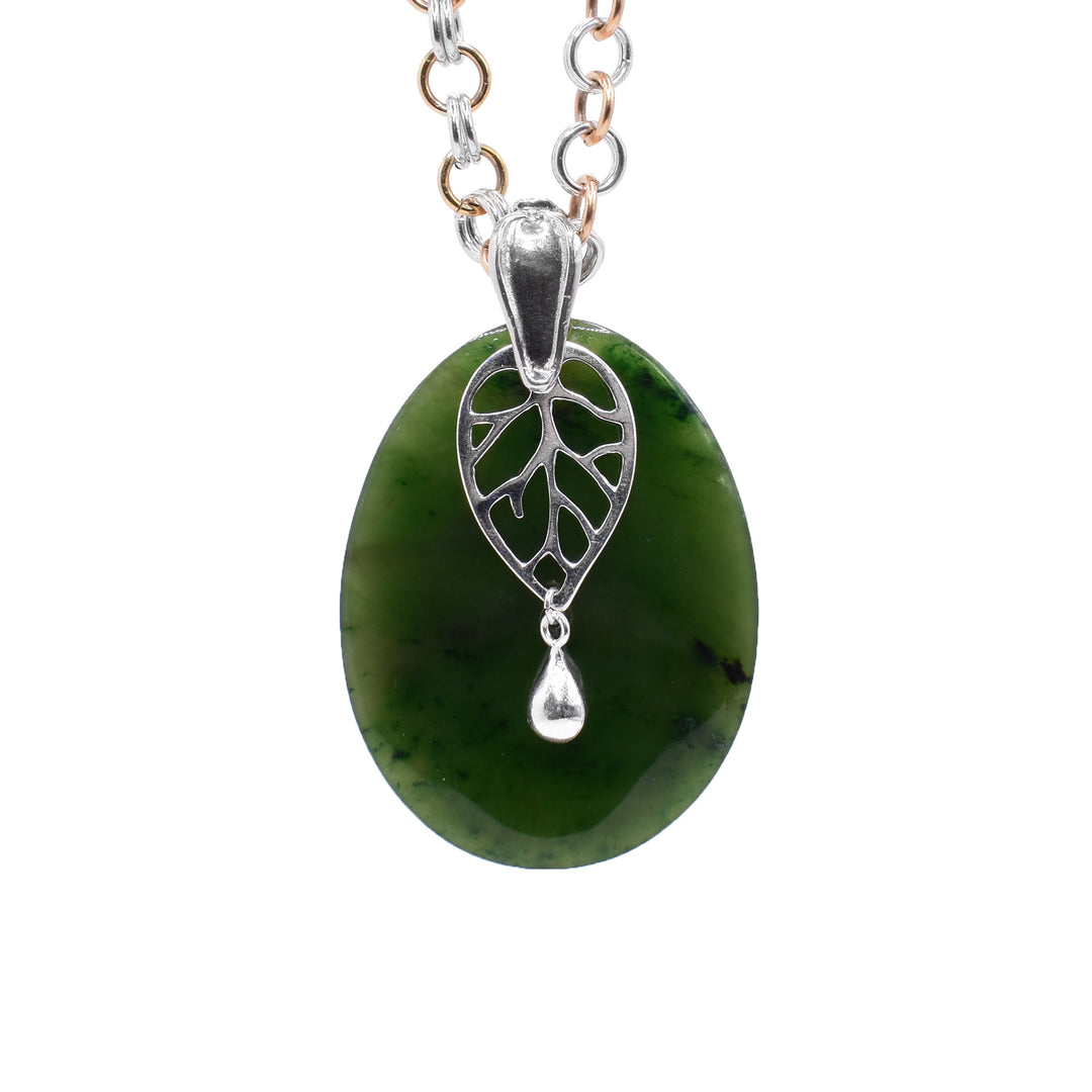 This jade pendant has a large, oval shaped BC jade stone with a cutout, sterling silver leaf charm.