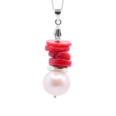 This red coral pendant has a large, freshwater pearl at the bottom with a sterling silver hoop stacked on top of it. There are four, round and flat red coral pieces stacked above those. The piece is held together with a small silver bead and bail.