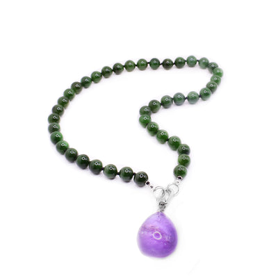 This jade beaded necklace has sphere shaped jade beads that are separated with spacers. There is a sterling silver chain link with a detachable amethyst pendant that is teardrop shaped.