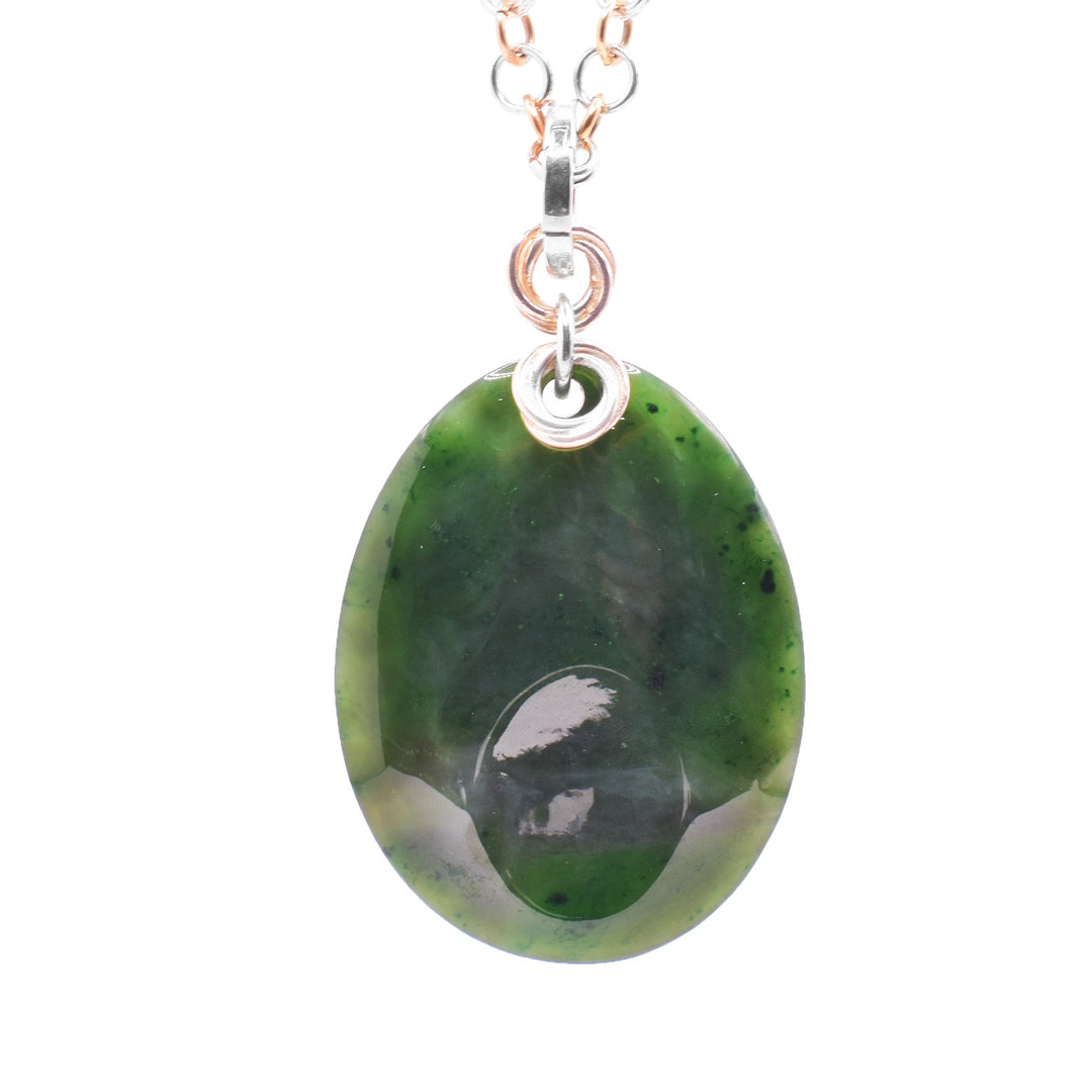 This large jade pendant has an oval shaped gem that is used as a worry stone. The jade has a smooth, oval shaped divot that you can rub. At the top of the pendant there are sterling silver and gold filled chain links hooped through and connecting it to the jump ring.