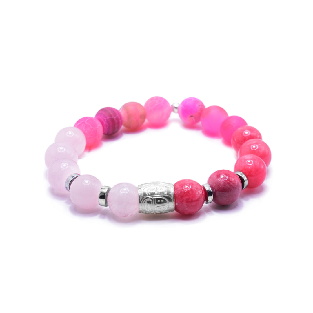 This bracelet with rose quartz has red quartz and rose quartz beads. The beads are small and sphere shaped. There is a sterling silver spirit bead in the center with the head of the Heron carved into it. There are two round and flat silver spacers.