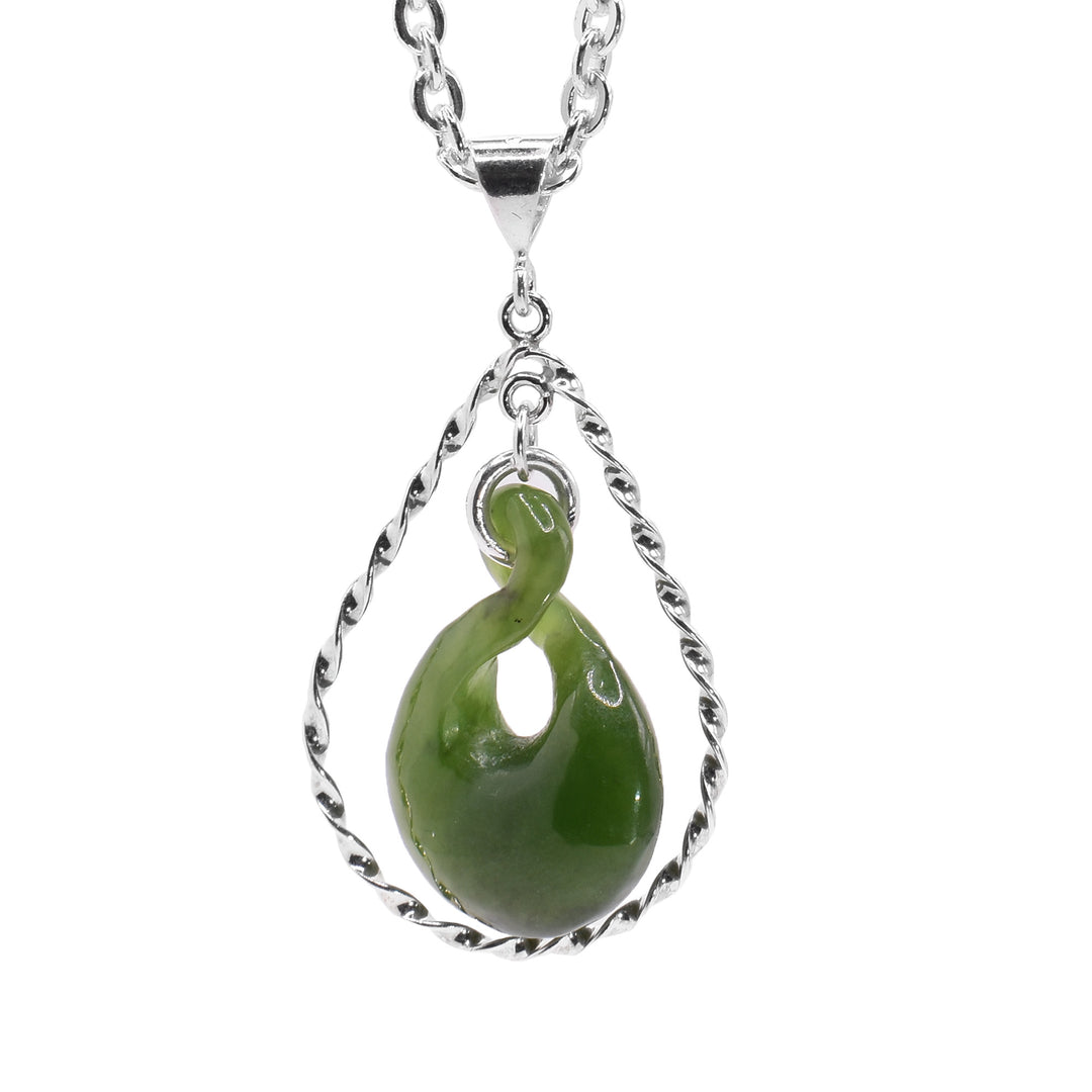 This jade pendant has a teardrop shaped jade piece that has a twisted design and small cutout in the center of it. There is a teardrop shape framing the jade pendant made from sterling silver wires that are finely twisted giving it a textured look.