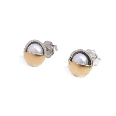 These pearl stud earrings have freshwater pearls laid in a sterling silver body with a 14K gold half circle covering half of each pearl.