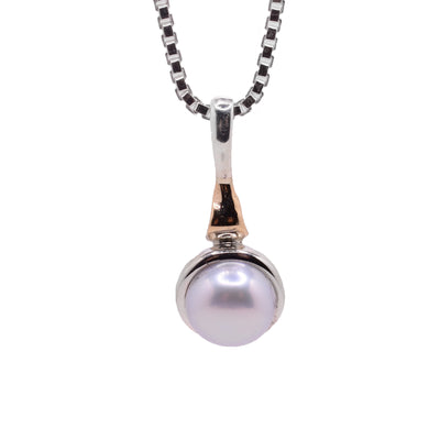 This silver pendant is made from sterling silver and 14K gold. There is a fresh water pearl attached to a bail on the pendant.