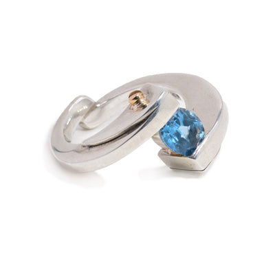 This abstract sterling silver and gold ring has two half circle pieces attached at the bottom of the ring. At the top of the ring, between the two pieces is a topaz gemstone with two 14K gold studs.