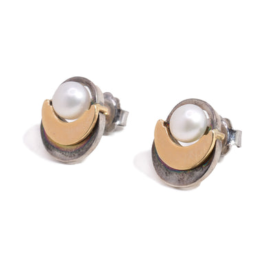 These pearl stud earrings have a sterling silver crescent going around a fresh water pearl with a smaller 14K gold crescent on top of the silver one.