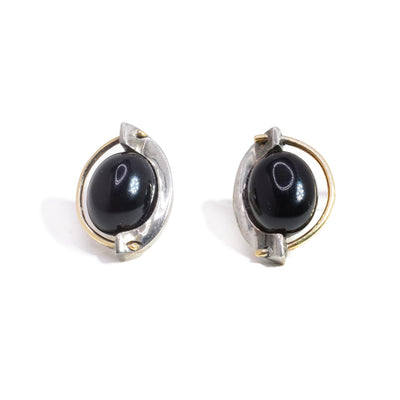 These black onyx earrings have sterling silver cradles holding round black onyx gems. There is also a 14K gold wire running around the gem. 