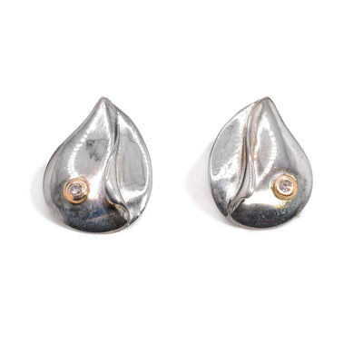 These sterling silver diamond earrings are teardrop shaped and have diamonds wrapped in 14K gold on them.