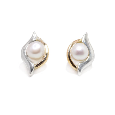 These pearl stud earrings are made with sterling silver and 14K gold. The earrings depict eyes and have freshwater pearls in the middle of them.