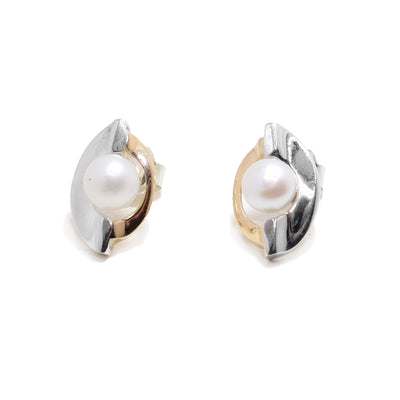 These pearl stud earrings have one sterling silver band and one 14K gold band wrapping around a fresh water pearl in the center of each earring.