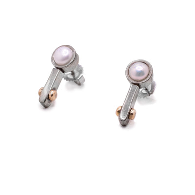 These sterling silver stud earrings have a pearl held by silver with a small arm reaching down from the pearl. at the end of these arms are two 14K gold beads.