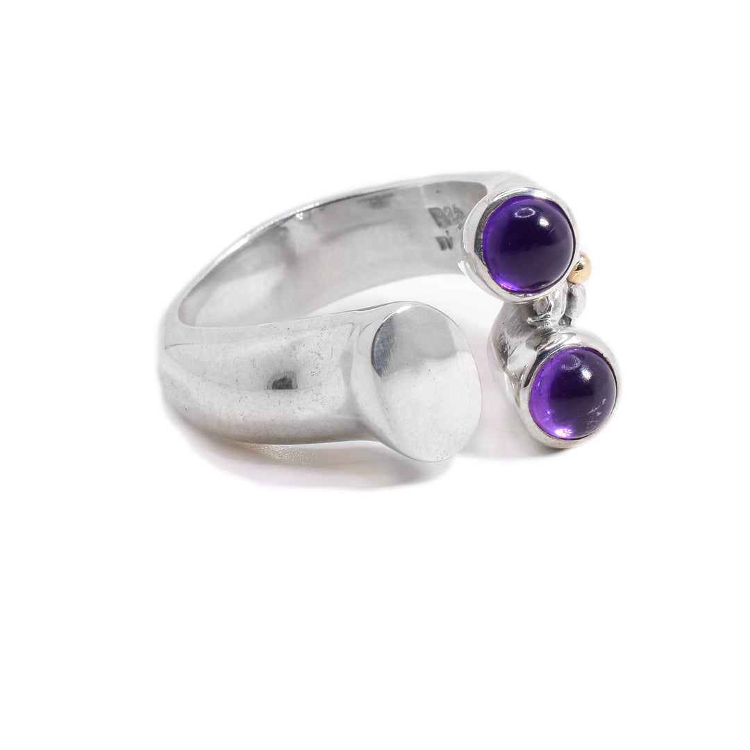 A split sterling silver band. One split side is flat, and the other has two circular amethyst stones. There is a gold bolt detail beside the amethyst stones.