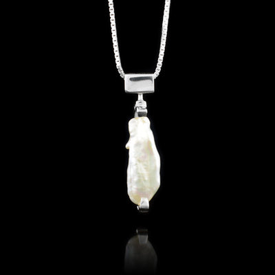 This baroque pearl pendant necklace has a sterling silver bail that is wide and rectangular. There is a long, baroque pearl that dangles from the bail horizontally. There is a 14K gold stud holding the pearl up from the bottom.