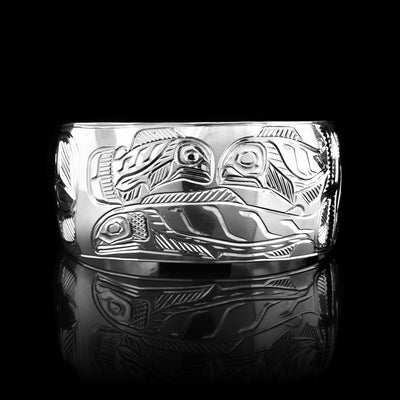 This sterling silver cuff bracelet has a wide band with depictions of the Bear and the Eagle carved onto the sides of the band and there are depictions of the Salmon carved onto the center of the band.