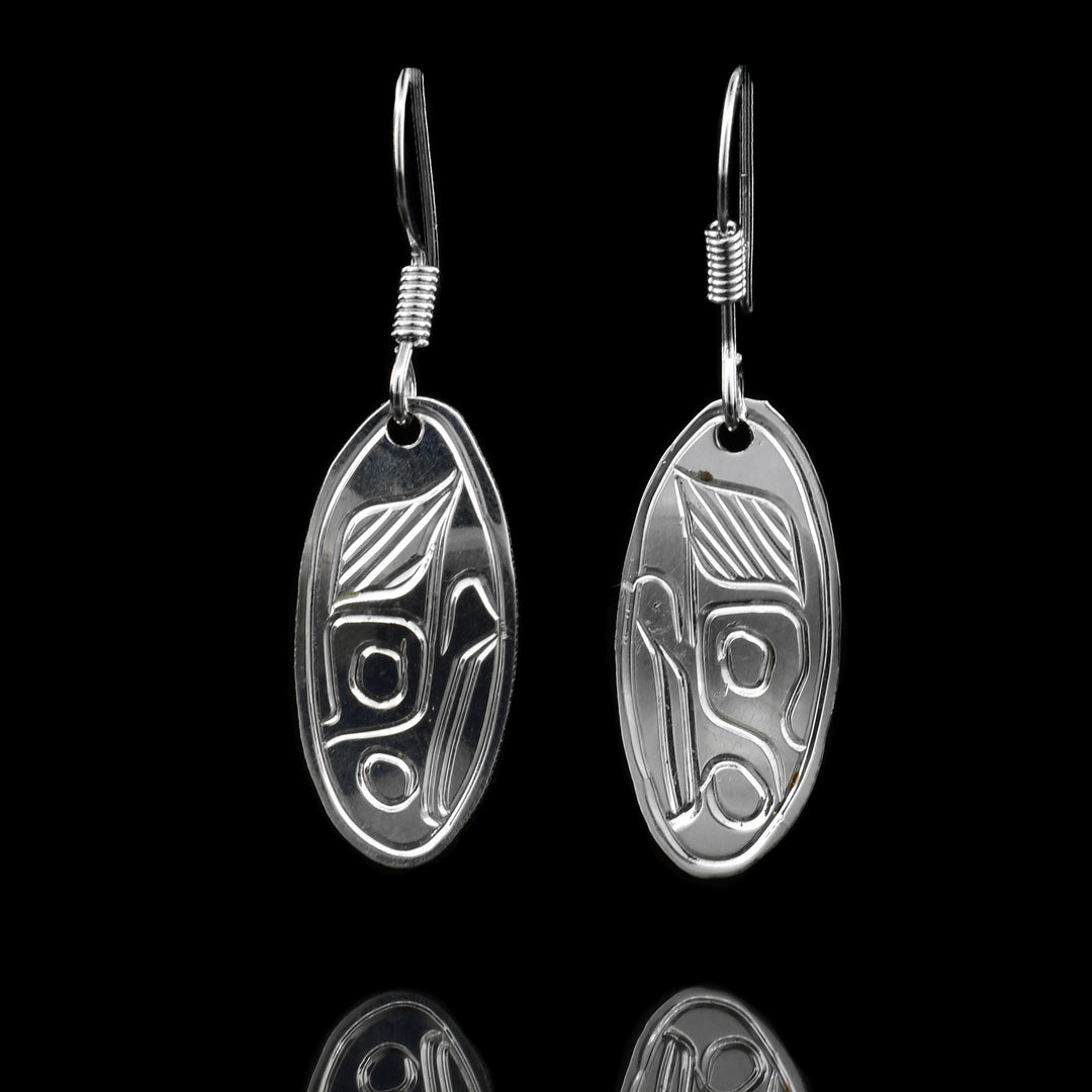 These sterling silver dangle earrings have thin, oval shaped hangs with depictions of the face of the Eagle carved into them.