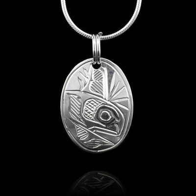 This sterling silver pendant is oval shaped and has a depiction of the Orca carved into the surface of it.