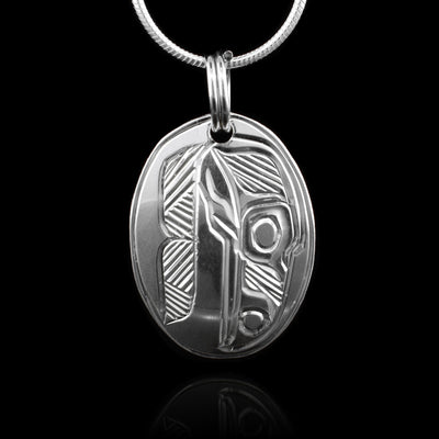 This sterling silver pendant is oval shaped and there is a depiction of the face of the Raven carved into the surface of it.