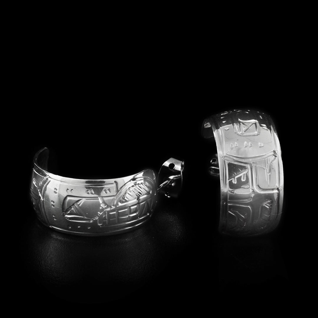These wide hoop earrings are made out of a flat piece of sterling silver on which a face of the Bear is carved .