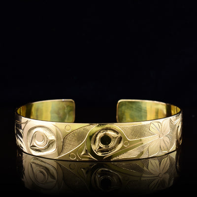 This Hummingbird bracelet cuff is made from solid 14K gold and has a single band with a gap in the back. There is a depiction of the Hummingbird and flowers that have been intricately carved into the surface of the band.