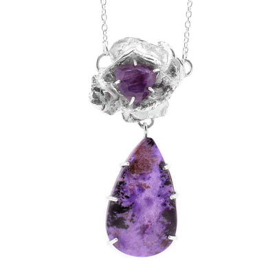 This unique gemstone necklace has a sterling silver flower with a large amethyst gem held in the middle. Below this charm is a large teardrop shaped Charoite pendant.