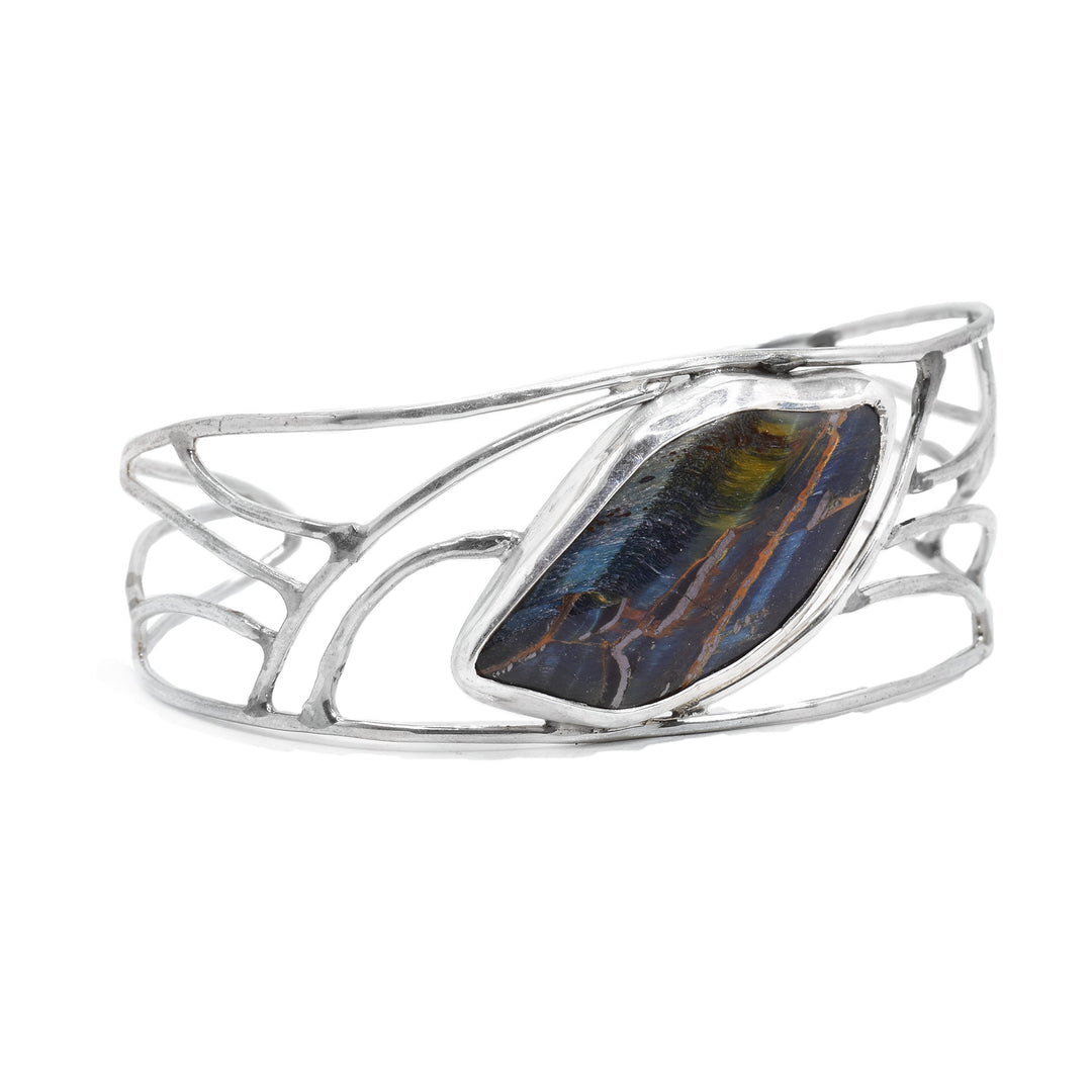 This sterling silver cuff bracelet is made from silver wires that are shaped into designs. There is an oval shaped blue tiger's eye gemstone in the center of the bracelet.