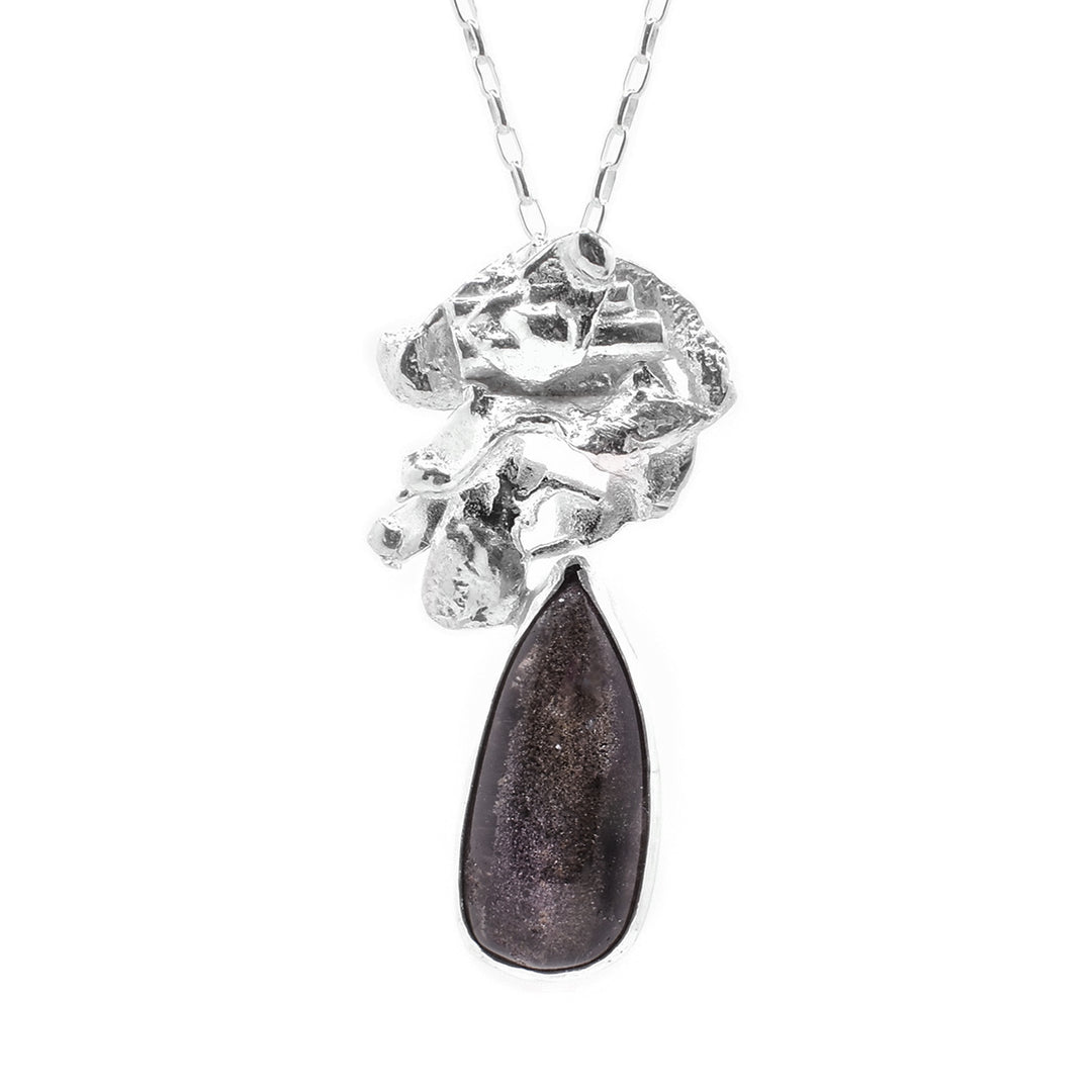 This garden quartz pendant necklace features a large, sterling silver piece above the gemstone. The piece has an abstract shape. Below this piece is a teardrop shaped garden quartz gem.